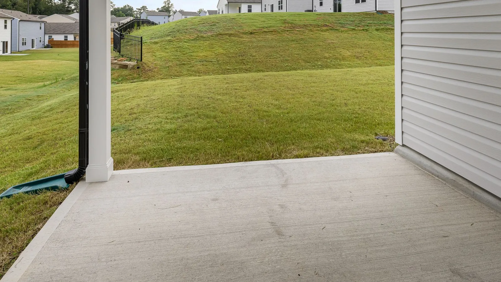 A finished covered concrete patio looking out across a mown lawn