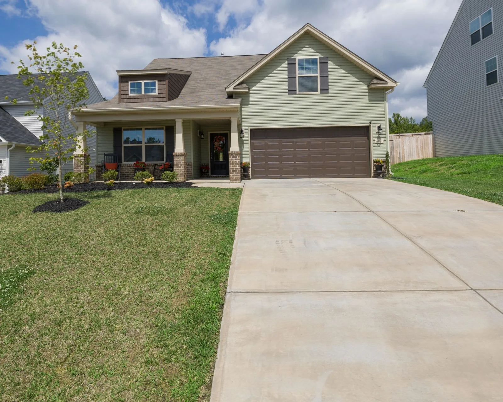 A finished concrete driveway leading up to a suburban home with a mown front lawn